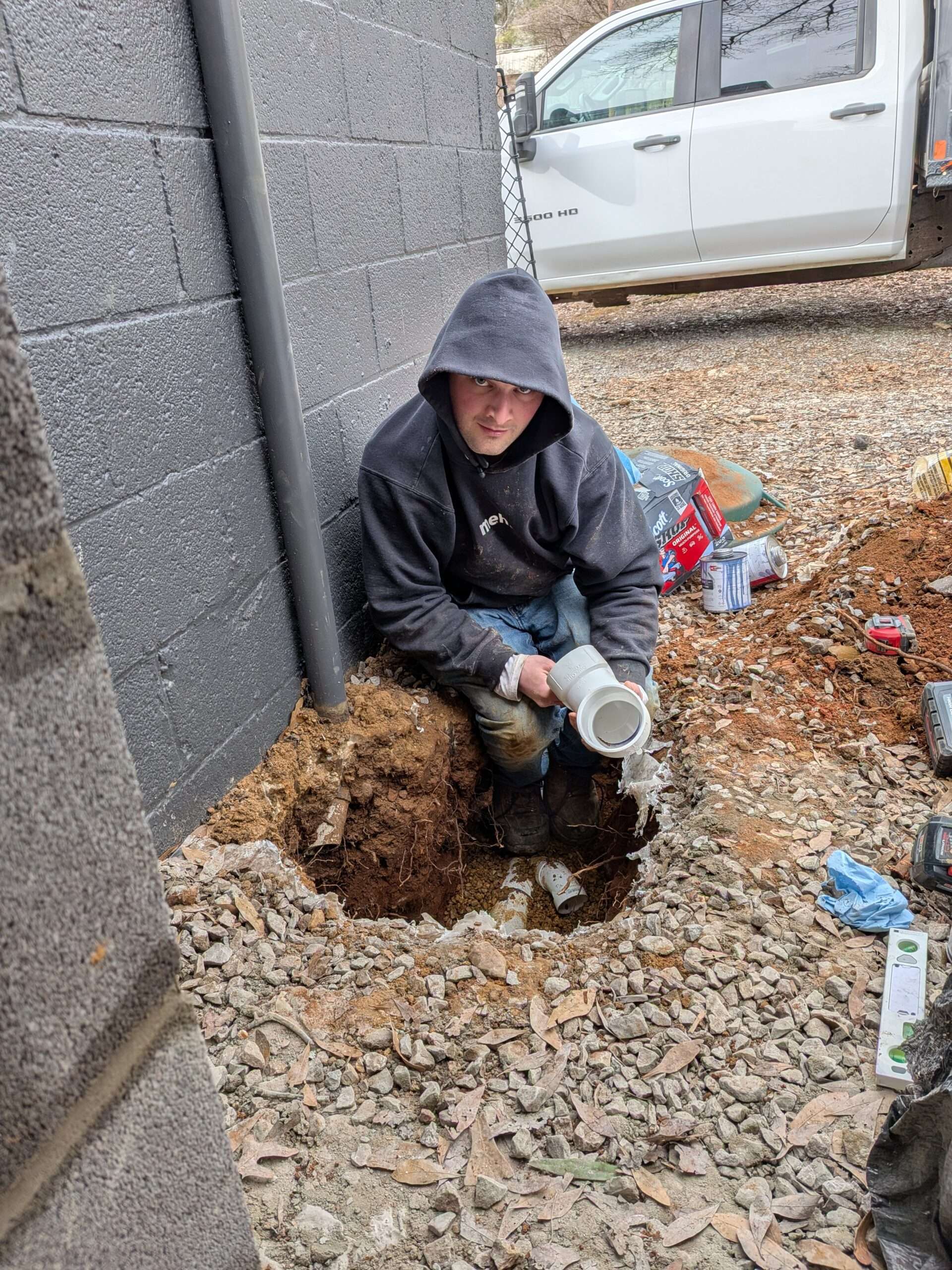 An expert plumber from Piper's Plumbing installing underground drainage piping next to a foundation in Dayton, TN