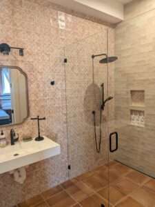 A modern bathroom remodel featuring custom tile work and a glass shower enclosure installed by plumbers in Dayton, TN